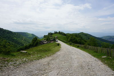 Road leading towards mountains against sky