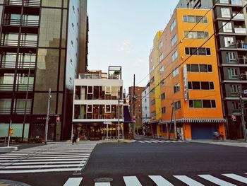 Road by buildings against sky in city