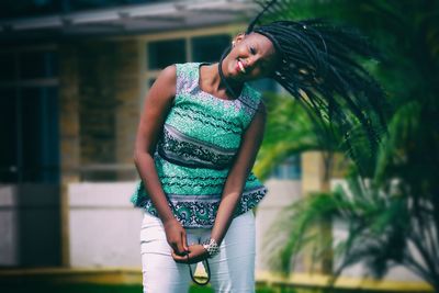 Happy young woman shaking head while standing at yard