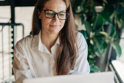 Portrait of young woman wearing sunglasses while sitting on table