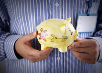 Midsection of businessman holding piggy bank