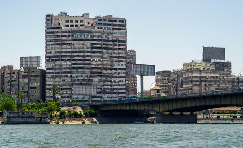 River by modern buildings against clear sky