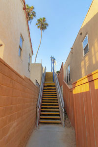 Low angle view of staircase amidst buildings against clear sky