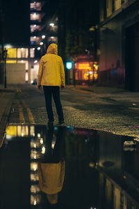 Rear view of woman walking on street at night