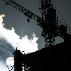 Low angle view of silhouette cranes against sky