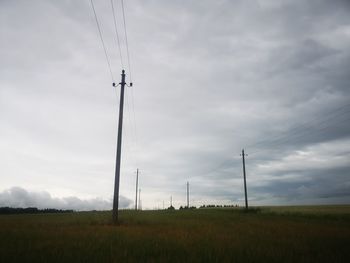 Low angle view of electricity pylon on field against sky