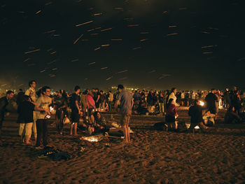 Crowd at music concert against sky at night