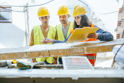 Woman talking to two construction workers on construction site