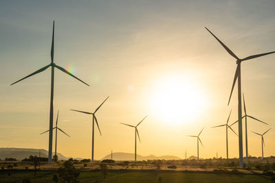 Windmill on field against sky during sunset