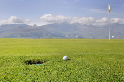 Golf ball on field against sky