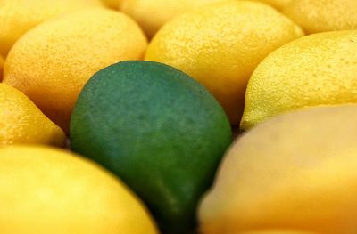Close-up of green and yellow lemons for sale at market stall