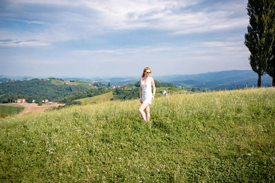 Full length of woman standing on grass against sky