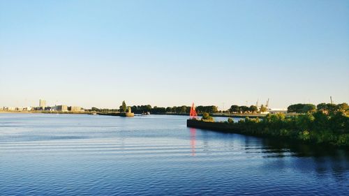 Scenic view of river by buildings against clear sky