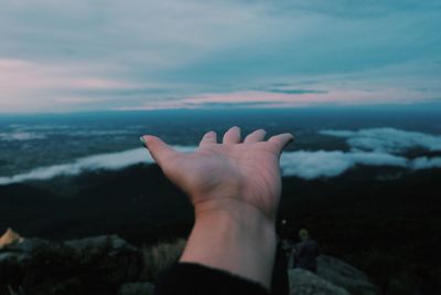 Close-up of hand on sea against sky