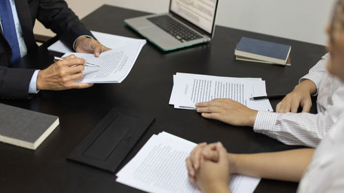 Midsection of colleagues working on table