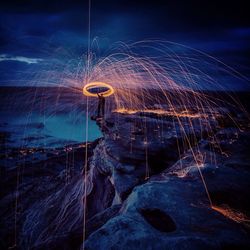 Man spinning steel wool on rock at night