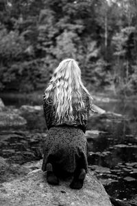 Rear view of woman kneeling at lakeshore