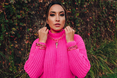 Portrait of beautiful young woman standing against pink plants