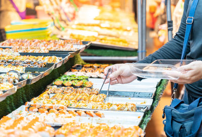 Woman use pliers selective sushi to buy in street food market.