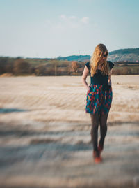 Full length of woman standing on land against sky