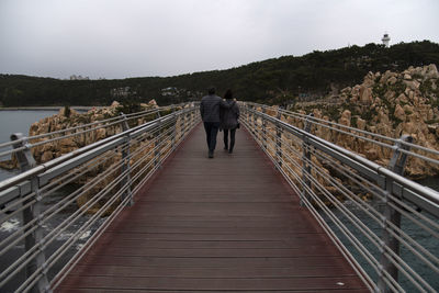 Rear view of man and woman walking on footbridge