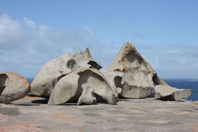 Rocks on rock formation by sea against sky