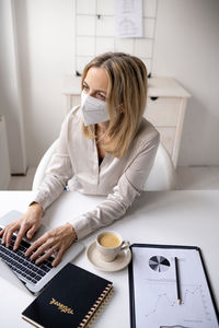 Woman using mobile phone while sitting on table