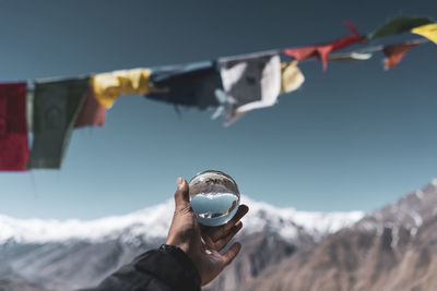 Close-up of hand holding ice against mountain