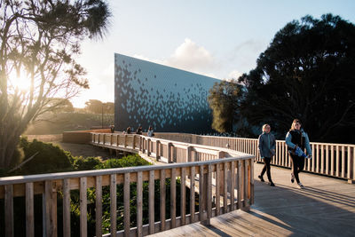 Men standing by railing against sky