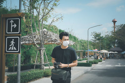 Young man traveller hand holding camera walking in street market