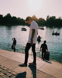 People standing by lake against sky