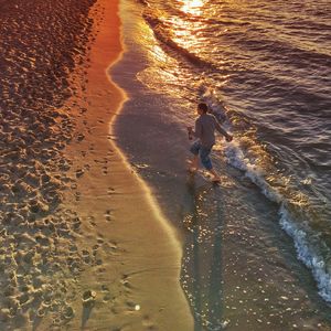 High angle view of man playing at beach during sunset