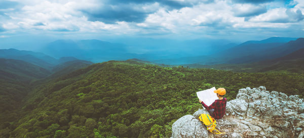 Rear view of woman standing on mountain against sky