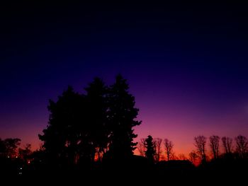 Silhouette trees against clear sky at sunset