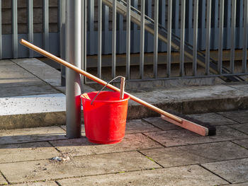 Red rose on railing by footpath by building