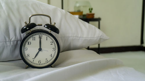 Close-up of alarm clock on bed