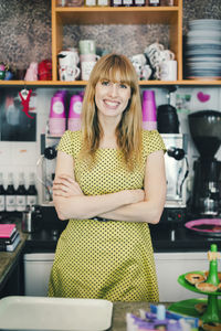 Portrait of confident barista standing arms crossed in cafe