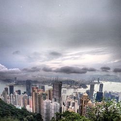 Low angle view of cityscape against cloudy sky