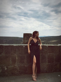 Full length of young woman standing against wall