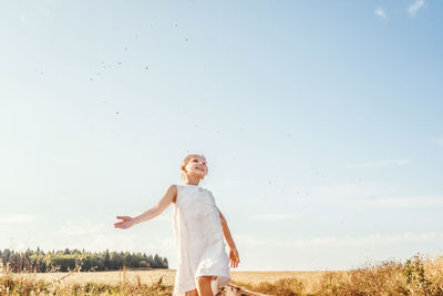 Happy boy standing on field against sky