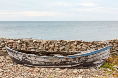 Old rotten rowboat at the beach with the sea in the background