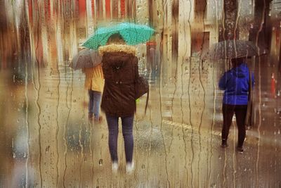 Rear view of woman with umbrella walking in city