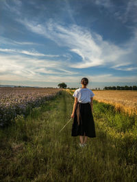 Rear view of man standing on field against sky