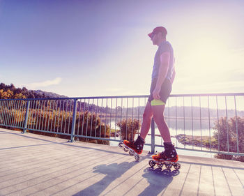 Inline skater ride on lake bridge. boy legs in in-line hard shell boots blades.