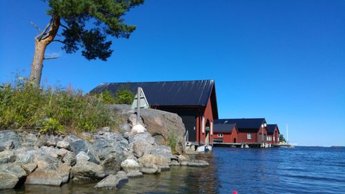 Built structure by sea against clear blue sky