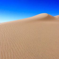 Scenic view of desert against clear blue sky