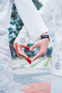 Midsection of couple making heart shape with hands