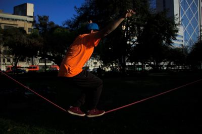 Boy with arms outstretched balancing on slackline at park