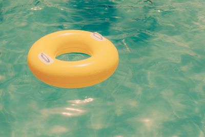 Yellow inflatable ring floating at swimming pool