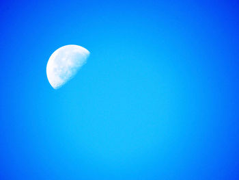 Low angle view of moon against blue sky